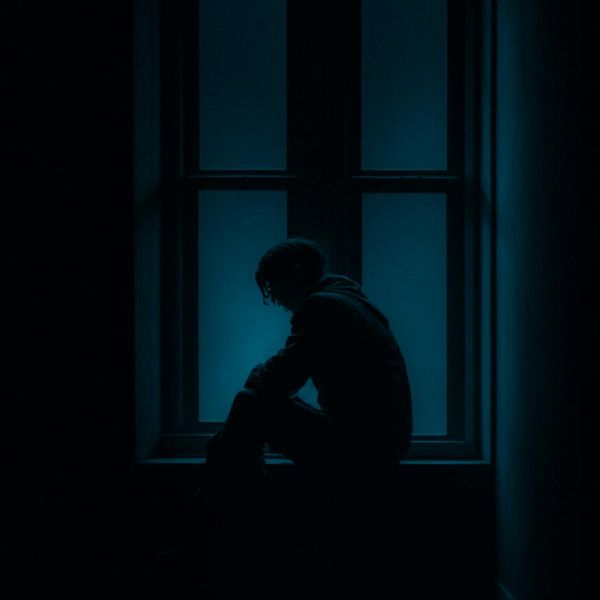 Person meditating in a minimalist dark room.
